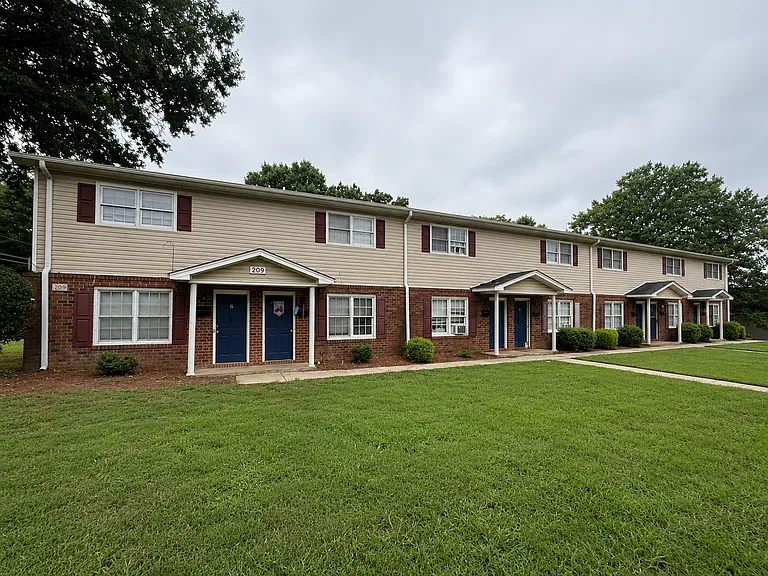 Brick and siding townhomes at McAden Place with individual front entrances and a green lawn